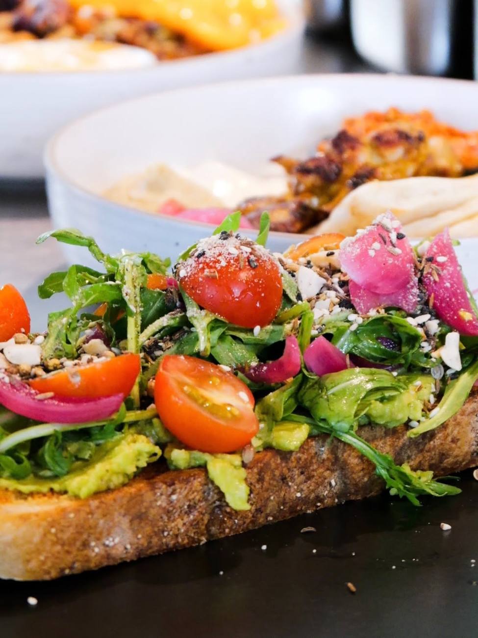 Smashed avocado on sourdough with tomato and pickled onion