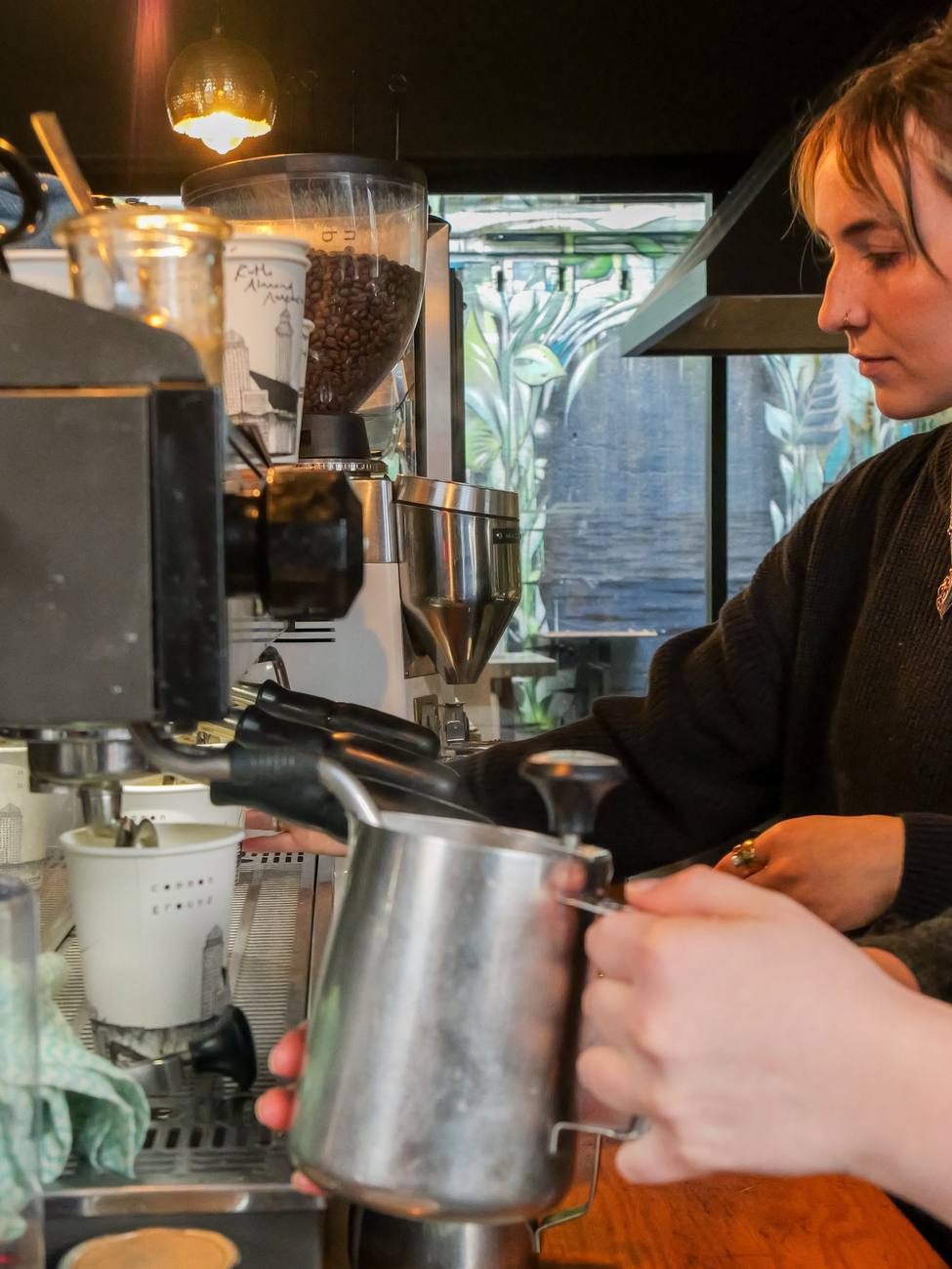A barista steaming milk at the coffee machine